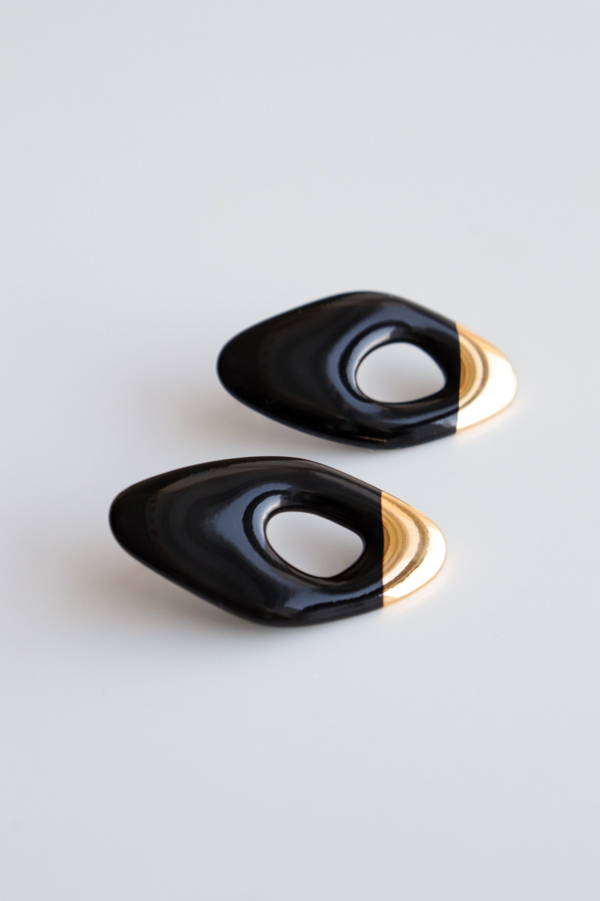 Flow Earrings by Rozenthal Jewelry: lightweight, waterproof, glossy black oval earrings with hollow centers and gold tips, handmade in Latvia. Displayed on a plain white background.