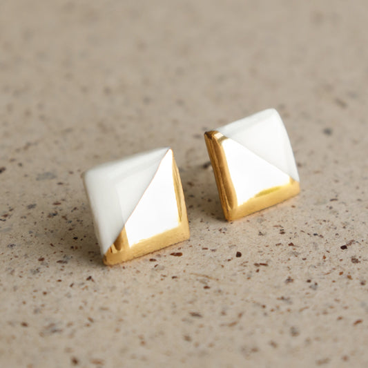 Edgy Studs / S by Rozenthal Jewelry—square stud earrings with a geometric white and gold design, shown on a speckled beige surface. Ideal for those who love minimalist jewelry.
