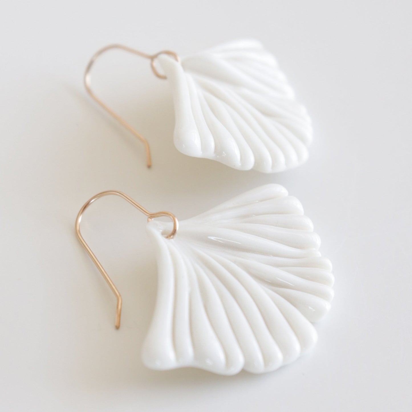 White ginkgo shaped earrings with gold hooks