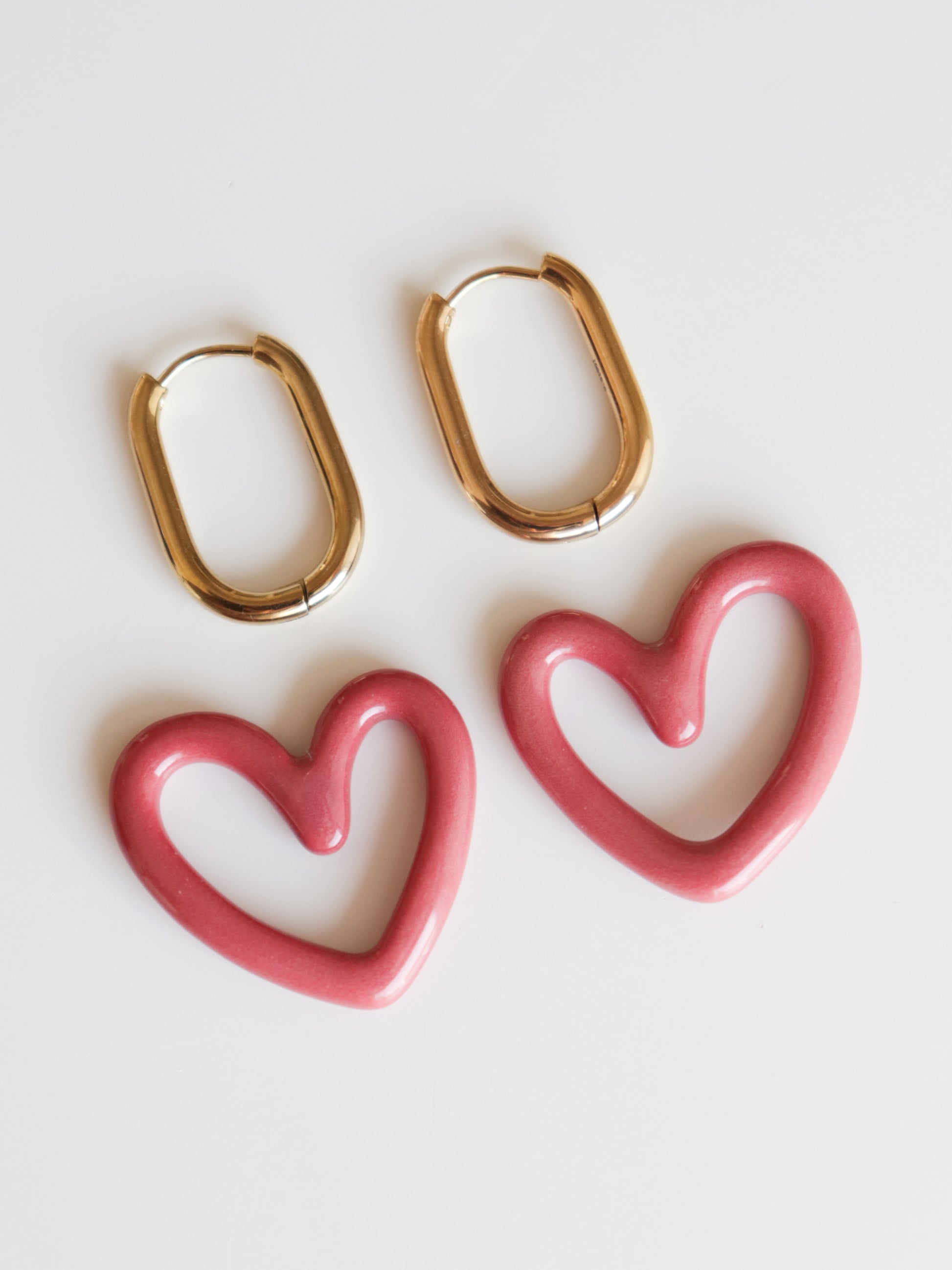 Two pairs of Rozenthal Jewelry earrings on a white background: gold ovals and pink open-heart Heart Earrings. Both are lightweight, waterproof, and perfect for all-day comfort and style.
