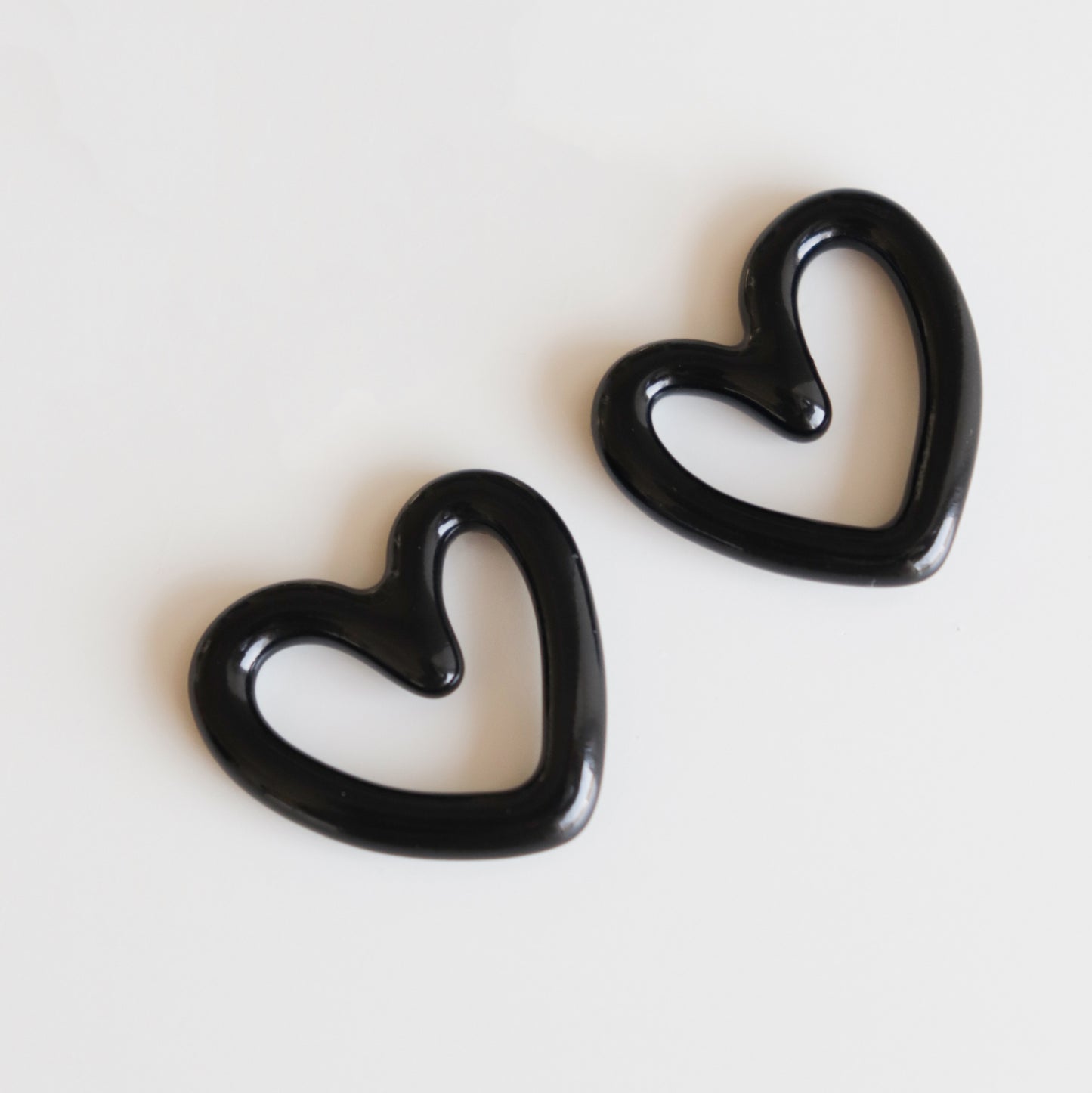 The Rozenthal Jewelry Heart Earrings, crafted in black porcelain with a hollow heart-shaped design, are displayed on a plain white background and angled slightly apart.