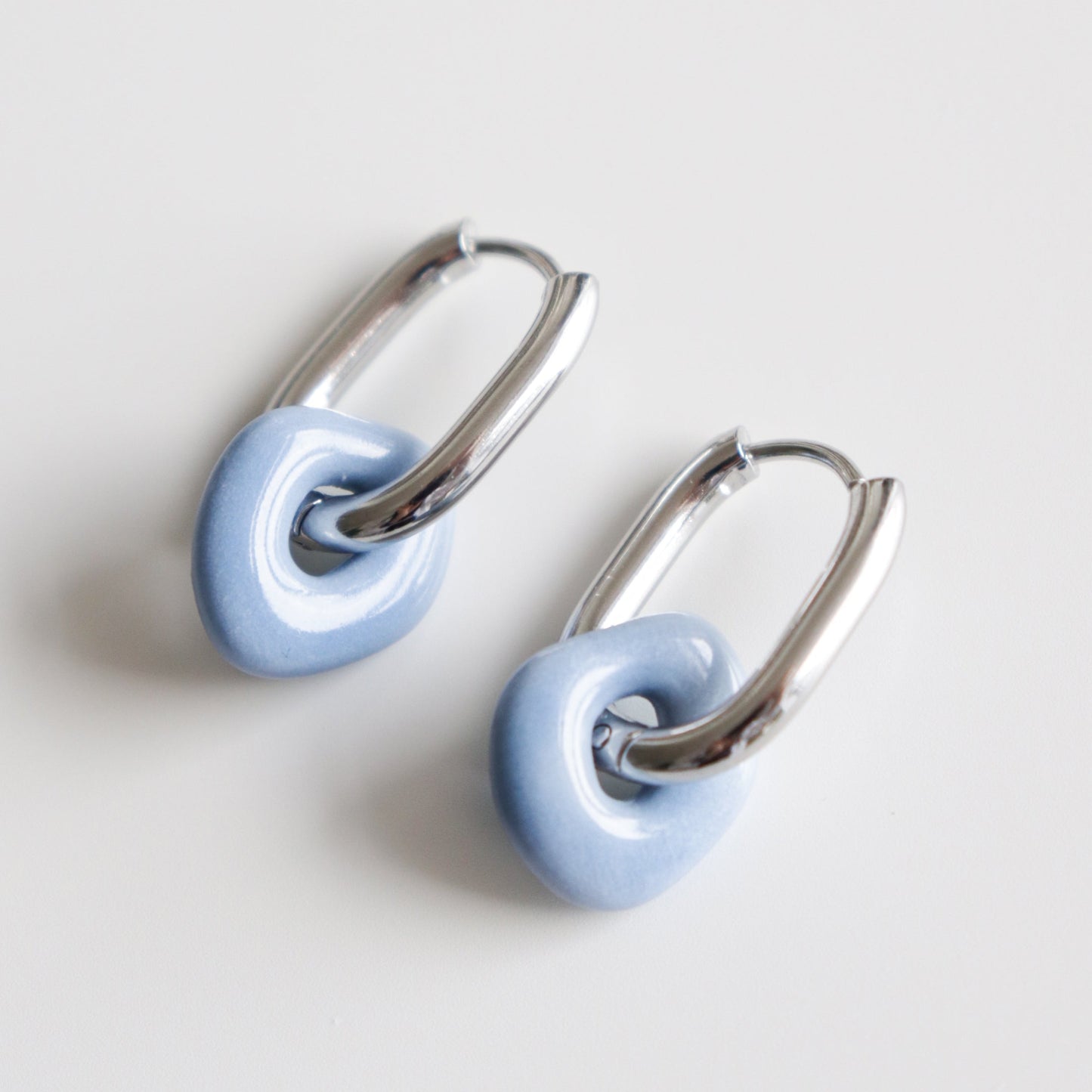 Pair of earrings with blue charms and silver hoops on a light gray background