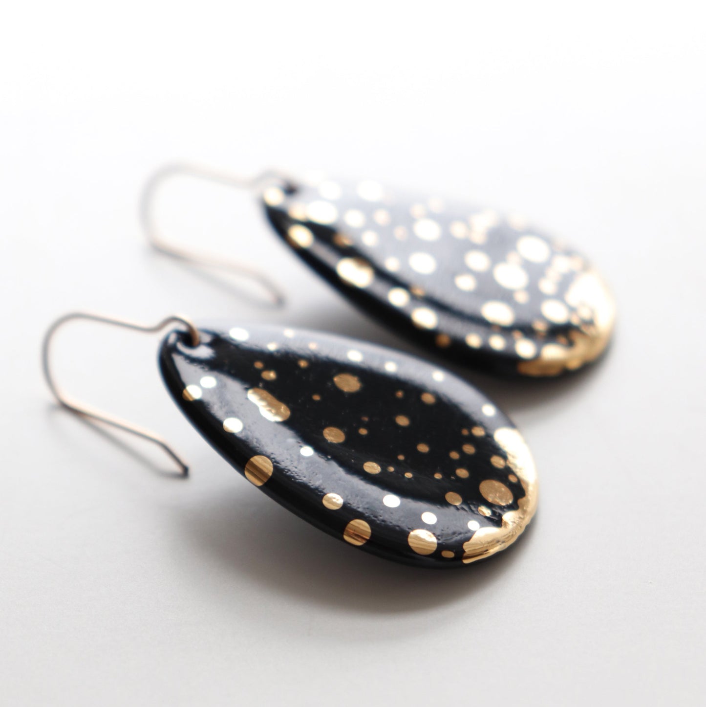 Rozenthal Jewelrys Drop Earrings / M feature handmade black teardrop shapes with gold and white splatter dots, beautifully displayed on a light background.