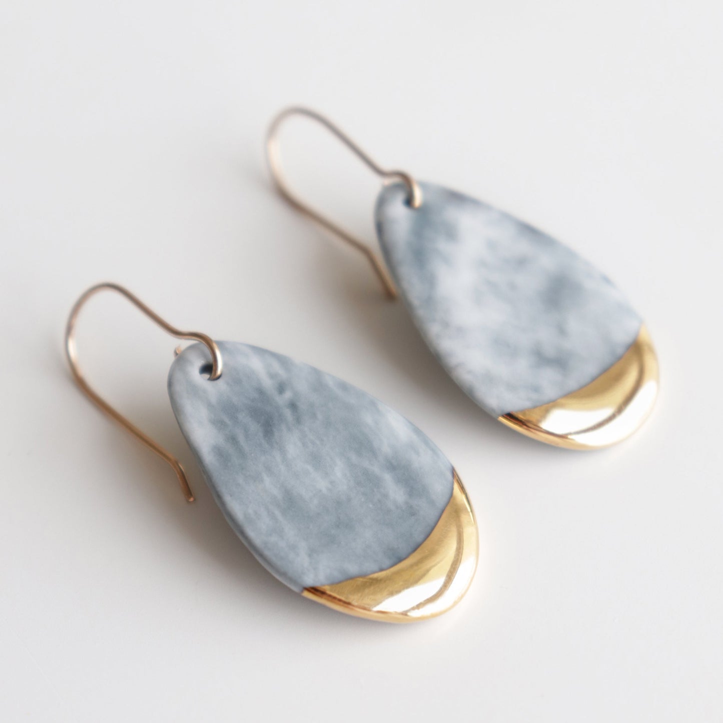 Drop Earrings / S by Rozenthal Jewelry—teardrop-shaped porcelain statement earrings with marbled gray tops and shiny gold bottoms, handmade in Latvia and set on gold hooks—shown on a white background.