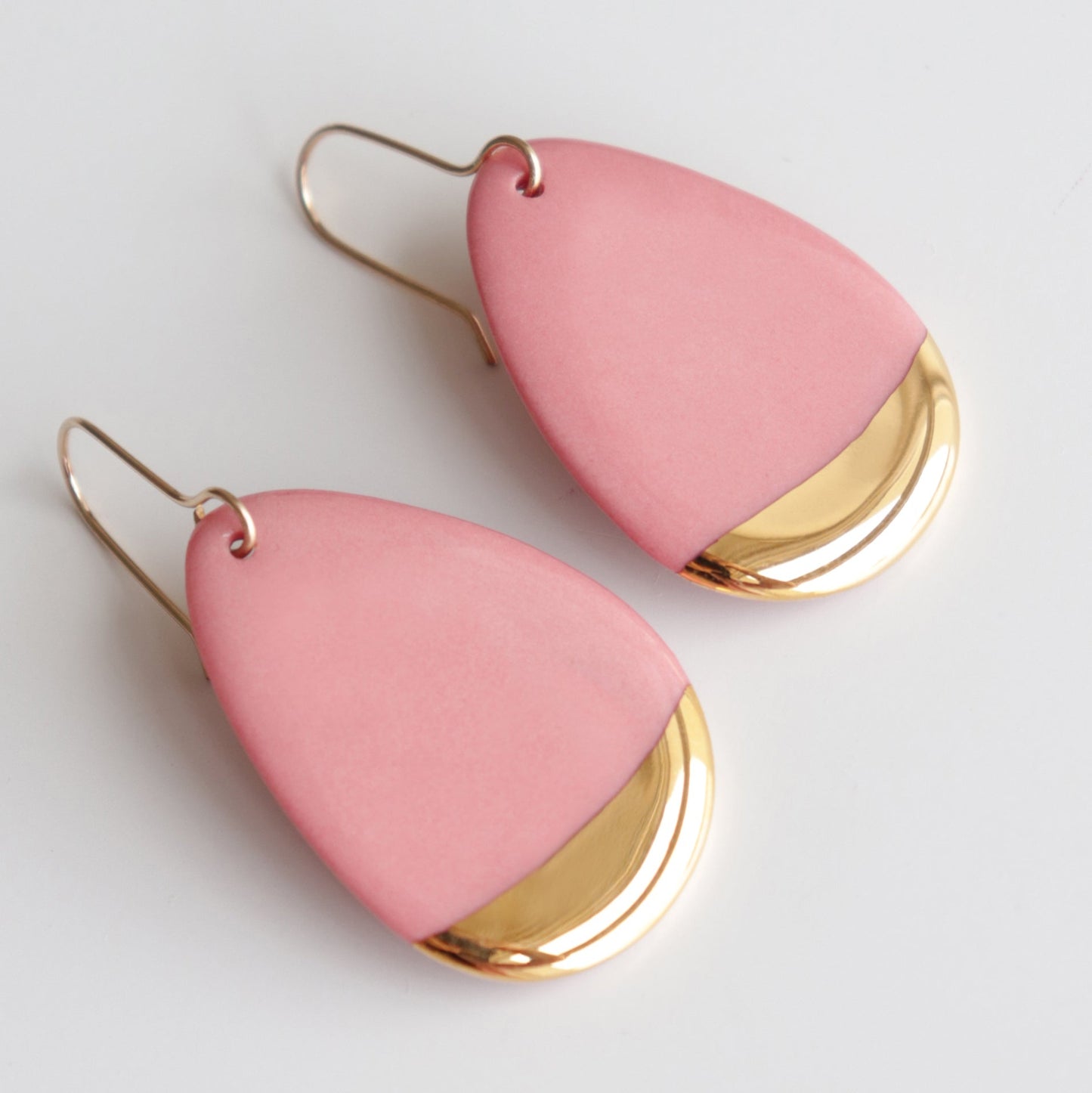 The Drop Earrings / M by Rozenthal Jewelry are teardrop-shaped pink dangle earrings with shiny gold accents, handmade in Latvia. These hypoallergenic designer earrings are shown on a white background.