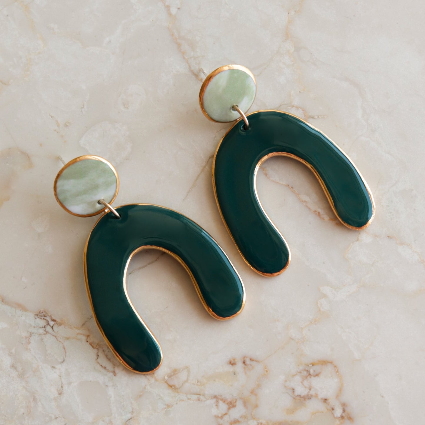 The Arquus Earrings by Rozenthal Jewelry feature modern porcelain with round pale green tops and dark green abstract U-shaped pendants edged in 24k gold—perfect for fans of unique handmade jewelry.