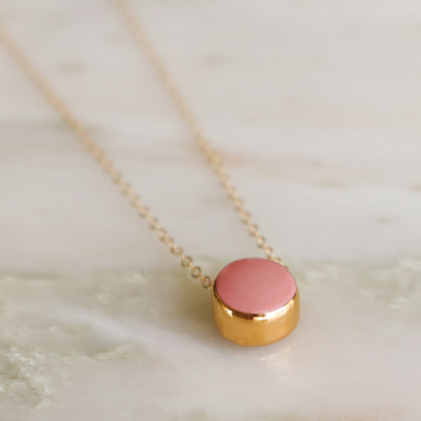 The Round Necklace by Rozenthal Jewelry is a minimalist gold chain with a small round pendant, shown elegantly on a light marble surface.