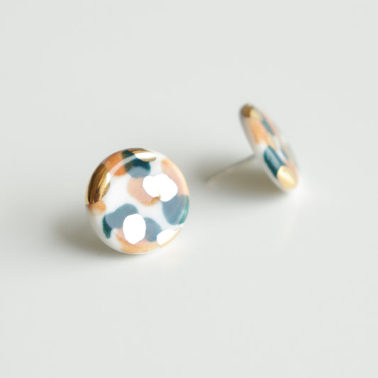 The Tache Studs / S by Rozenthal Jewelry are handmade round earrings featuring an abstract white, green, gold, and peach pattern, crafted in Latvia and shown on a white background.