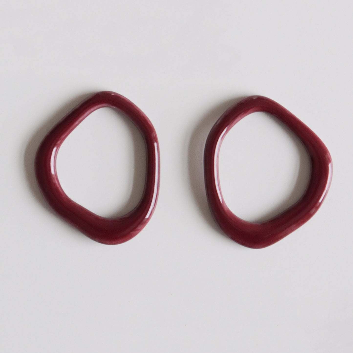 Two irregularly-shaped, dark red Arp Pearl Hoops by Rozenthal Jewelry are displayed side by side on a plain white background.