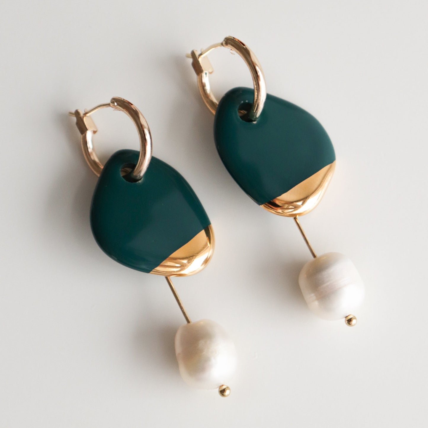 The Arp Pearl Hoops by Rozenthal Jewelry are modern earrings with gold hoops, dark green and gold abstract shapes, and dangling freshwater pearls—ideal for handmade jewelry lovers.
