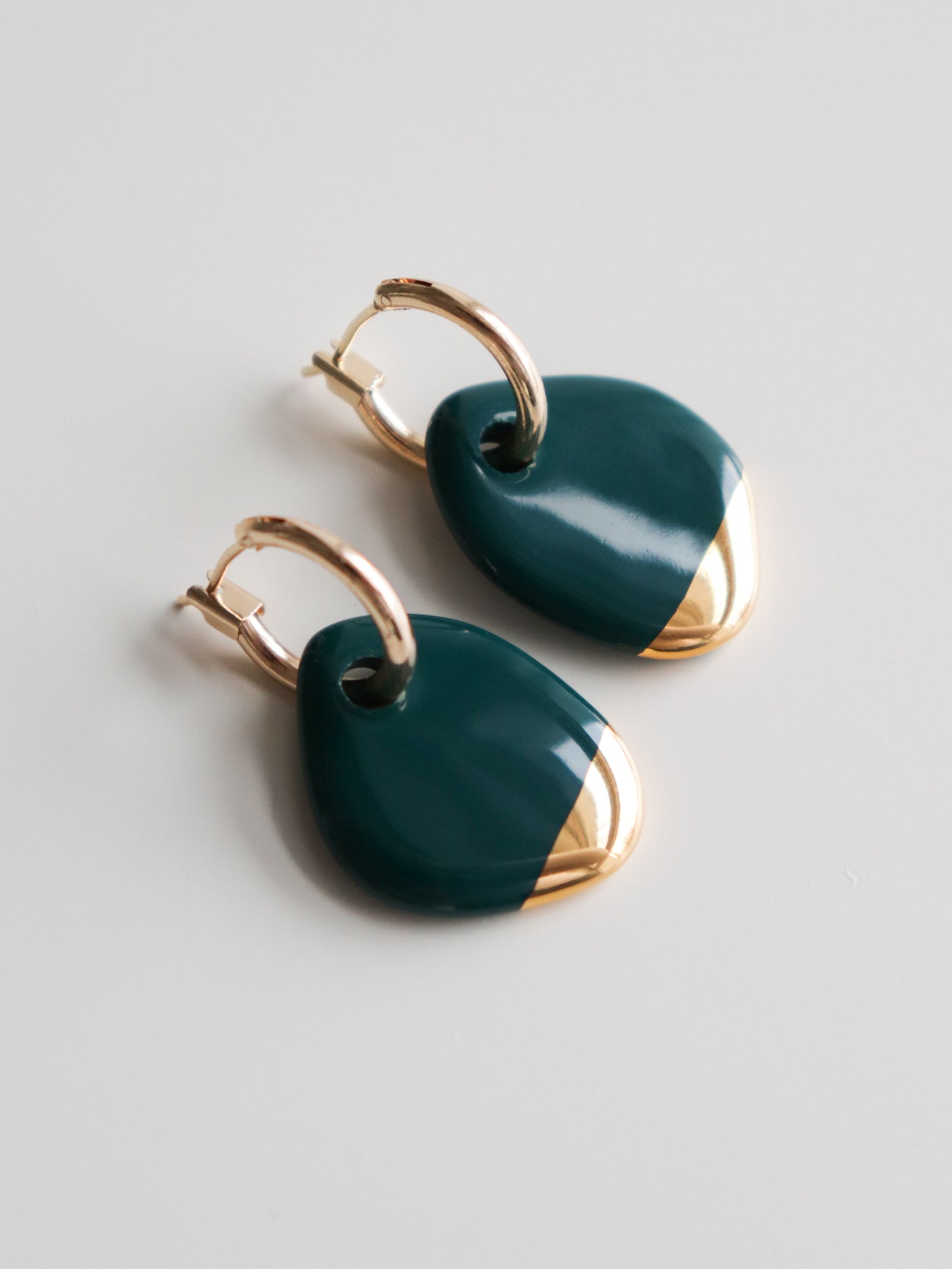 The Arp Pearl Hoops by Rozenthal Jewelry are handmade hoop earrings with dark green teardrop pendants and gold accents, shown on a plain white background.