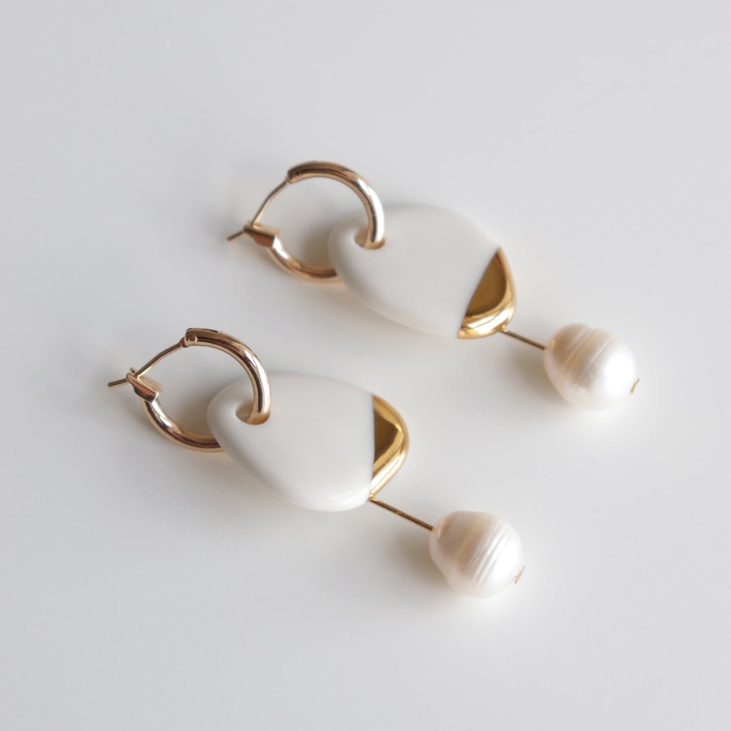 Arp Pearl Hoops by Rozenthal Jewelry: elegant handmade earrings with gold hoops, white geometric accents, and round pearl-like beads, shown on a plain white background.