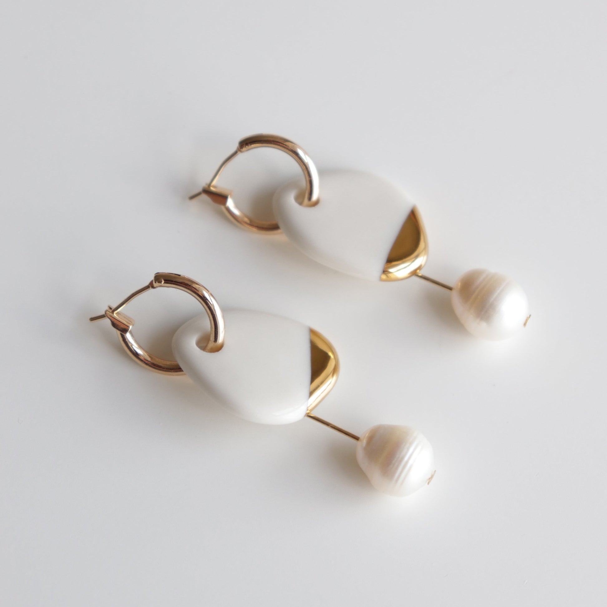 Arp Pearl Hoops by Rozenthal Jewelry: elegant handmade earrings with gold hoops, white geometric accents, and round pearl-like beads, shown on a plain white background.