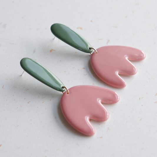 The Tulip Earrings by Rozenthal Jewelry feature handmade green oval ceramic tops and pink flower-shaped pendants—ideal for lovers of unique porcelain jewelry. Displayed on a light textured surface.