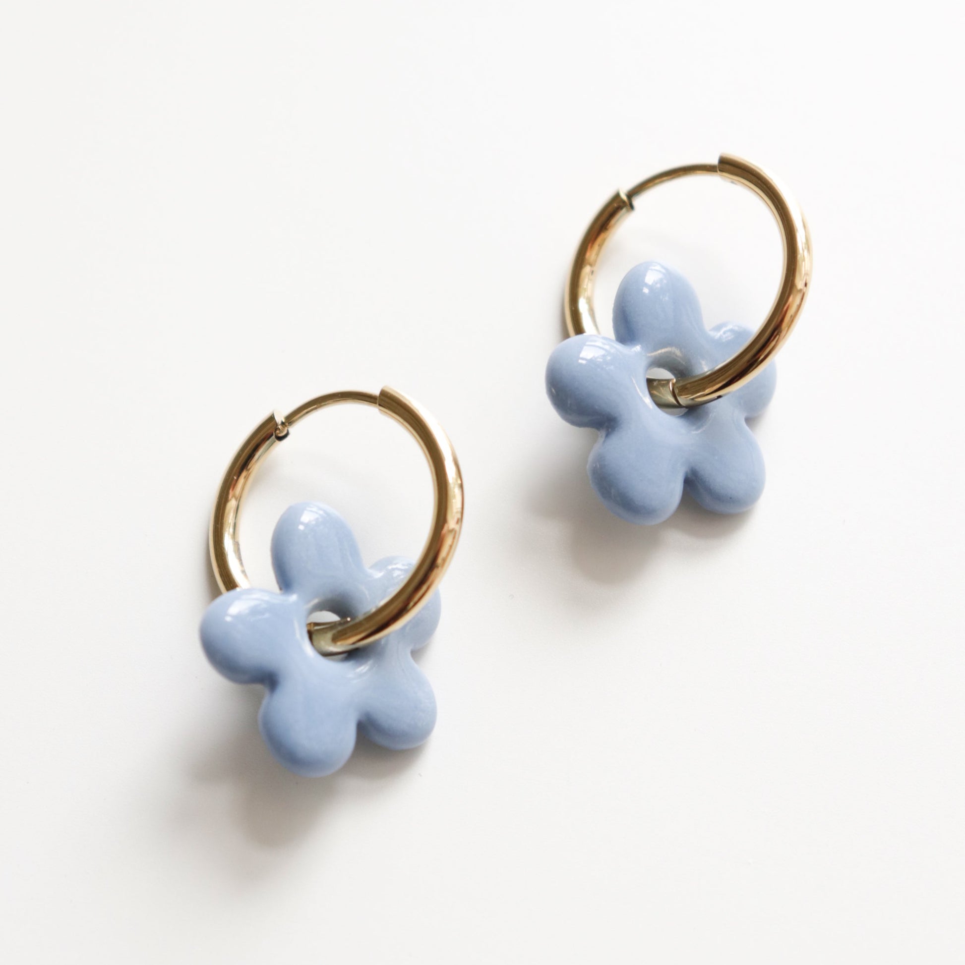 Pair of light blue flower-shaped hoop earrings on a white background