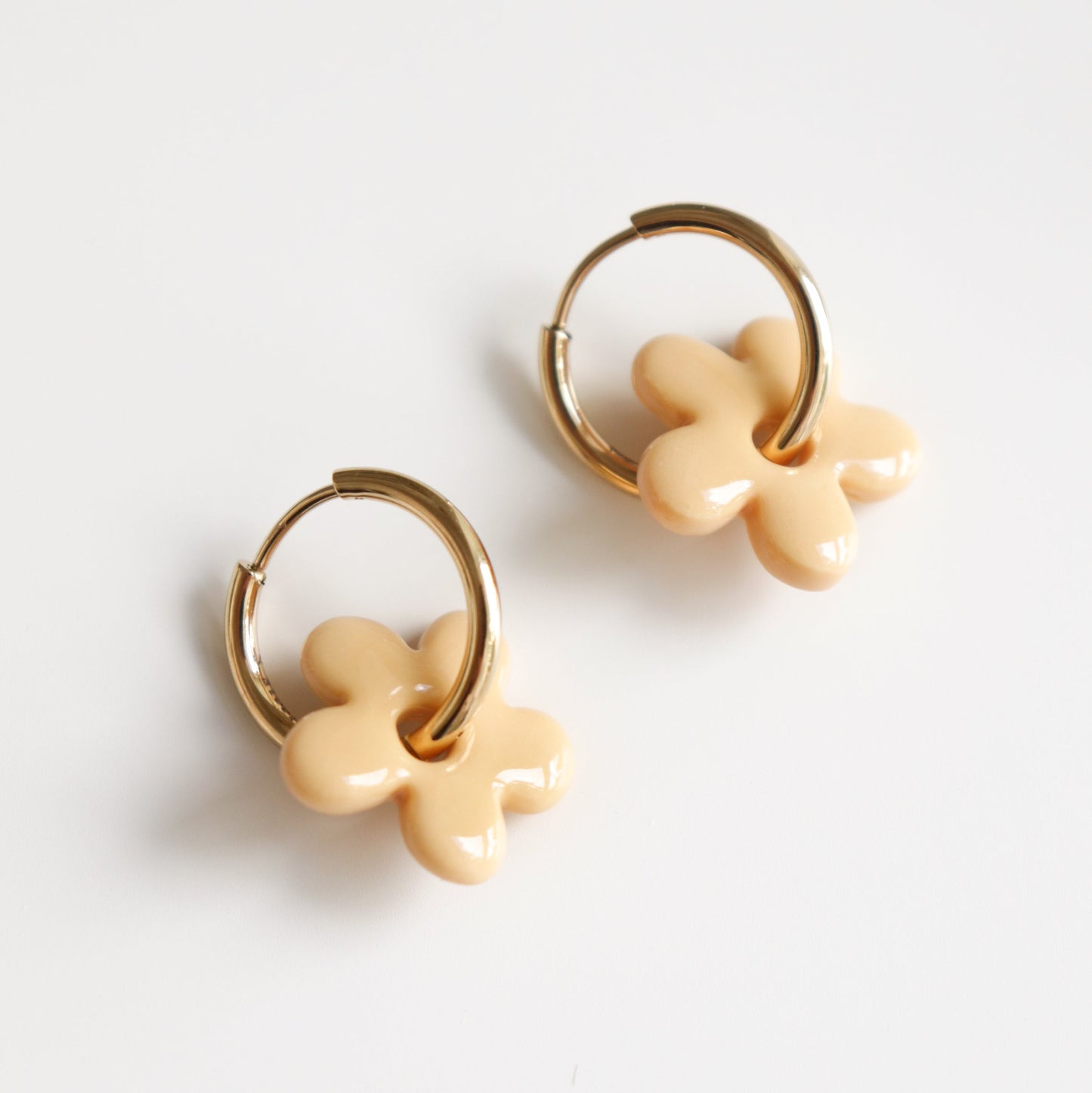 Pair of gold hoop earrings with yellow flower-shaped charms on a white background