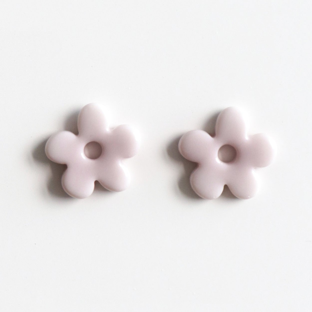 Two light purple flower-shaped earrings on a white background