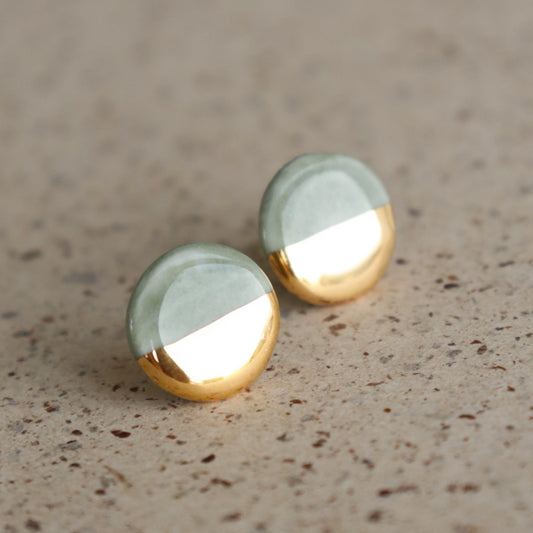 The Rozenthal Jewelry Round Studs / XS feature a two-tone design: matte silver on top and shiny gold below. These minimalist earrings rest on a speckled beige surface, adding a refined touch to your everyday style.