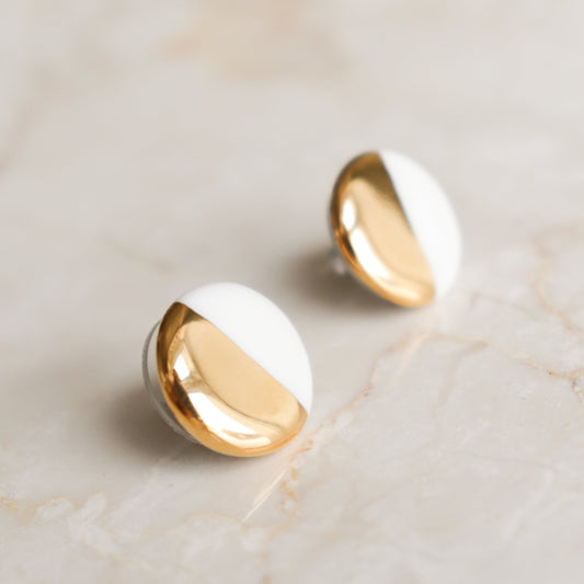 Round Studs / S by Rozenthal Jewelry feature a diagonal split design in shiny gold and smooth white—an elegant choice for minimalists, shown on a light marble surface.