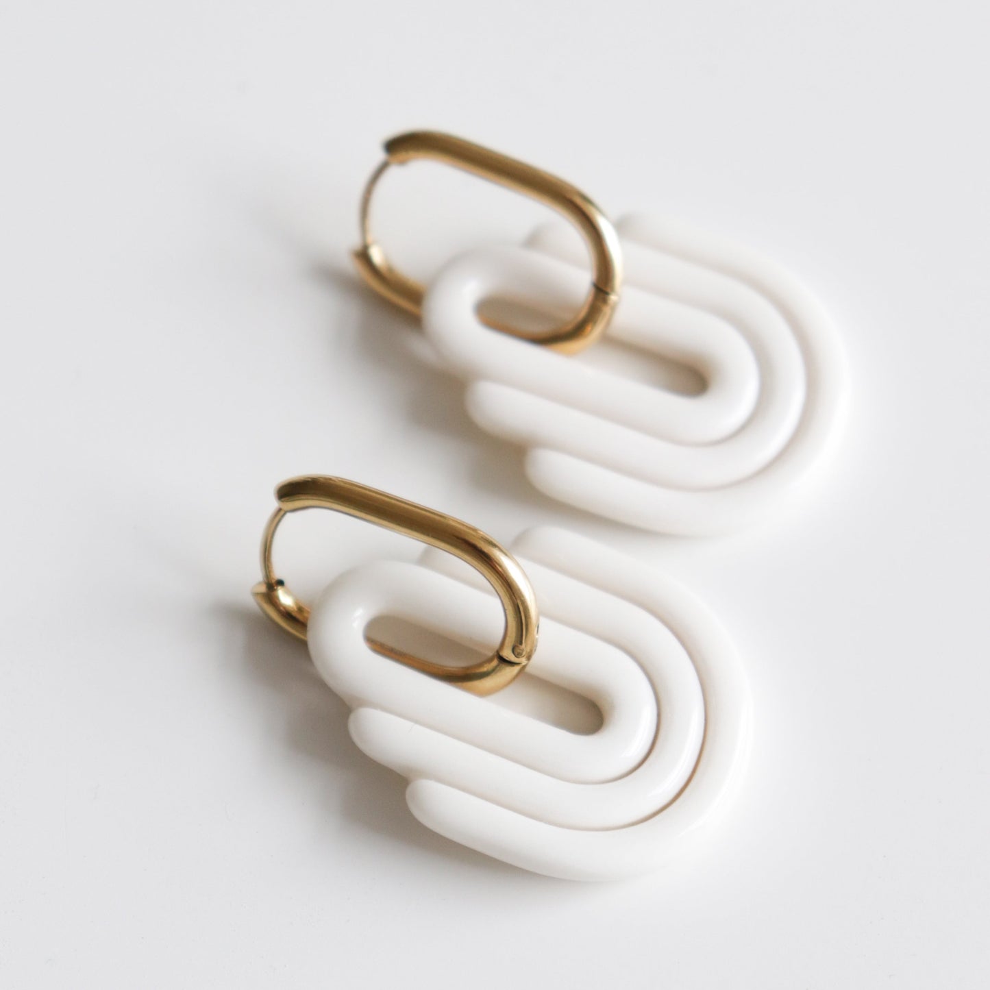 Art Deco Earrings by Rozenthal Jewelry: modern, hypoallergenic designer gold hoops with chunky white oval and rectangular shapes, handmade in Latvia and shown on a white background.