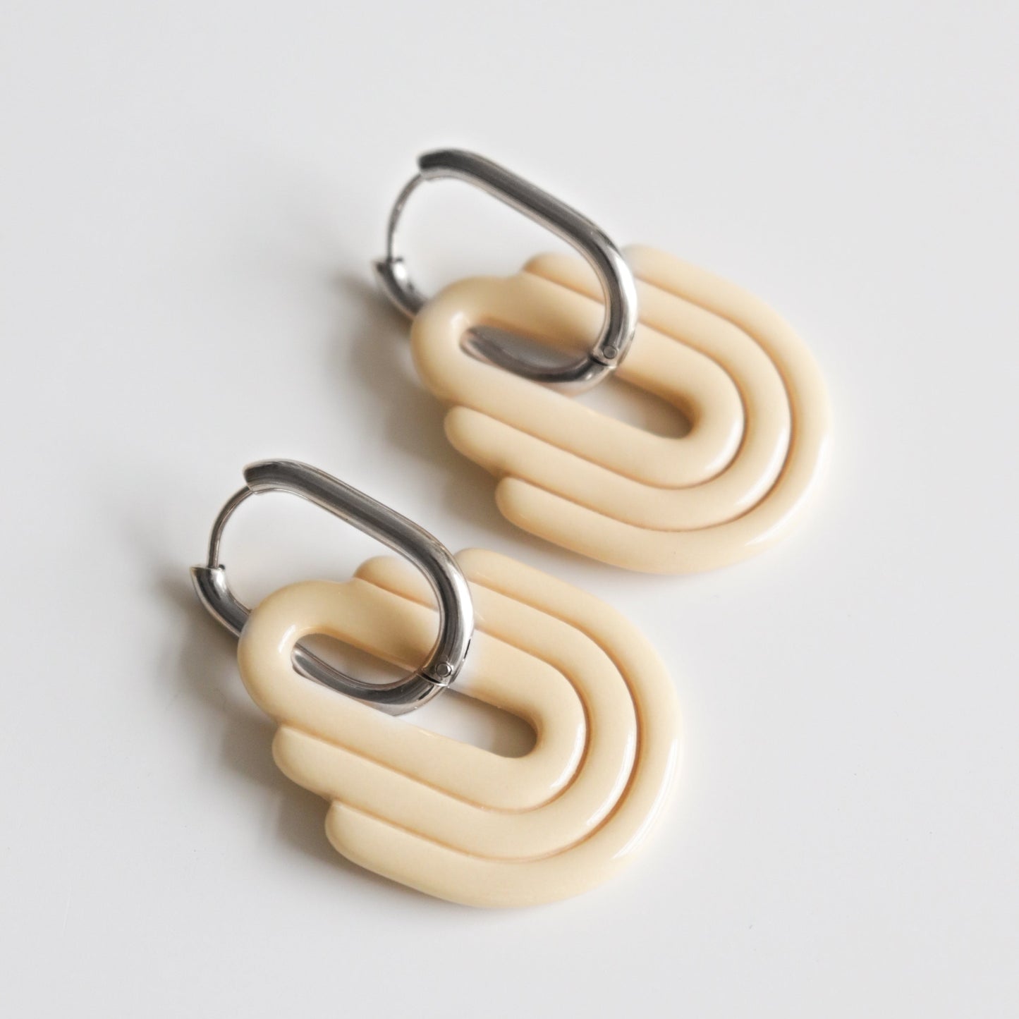 Discover the Art Deco Earrings by Rozenthal Jewelry—modern, chunky cream-colored handmade pieces with layered oval shapes on silver hoops. Perfect sustainable jewelry for elevating your everyday style.