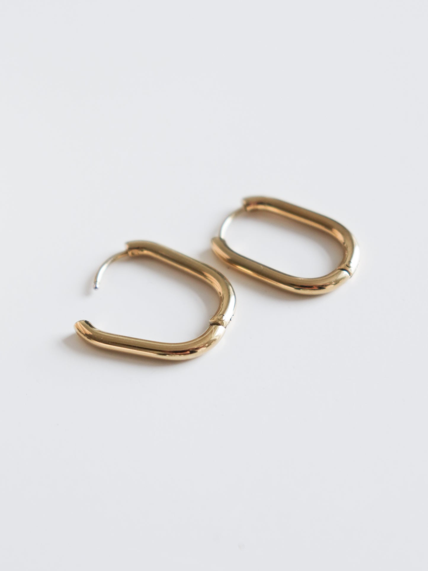 The Rozenthal Jewelry Large Hoops are gold-colored, rounded rectangular stainless steel earrings shown on a plain white background.