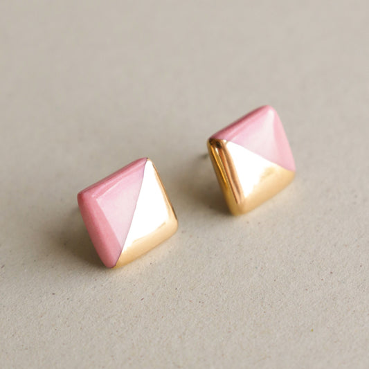 Edgy Studs / S by Rozenthal Jewelry—square stud earrings with a gold and soft pink geometric design—are shown on a neutral beige surface, ideal for minimalist jewelry lovers.
