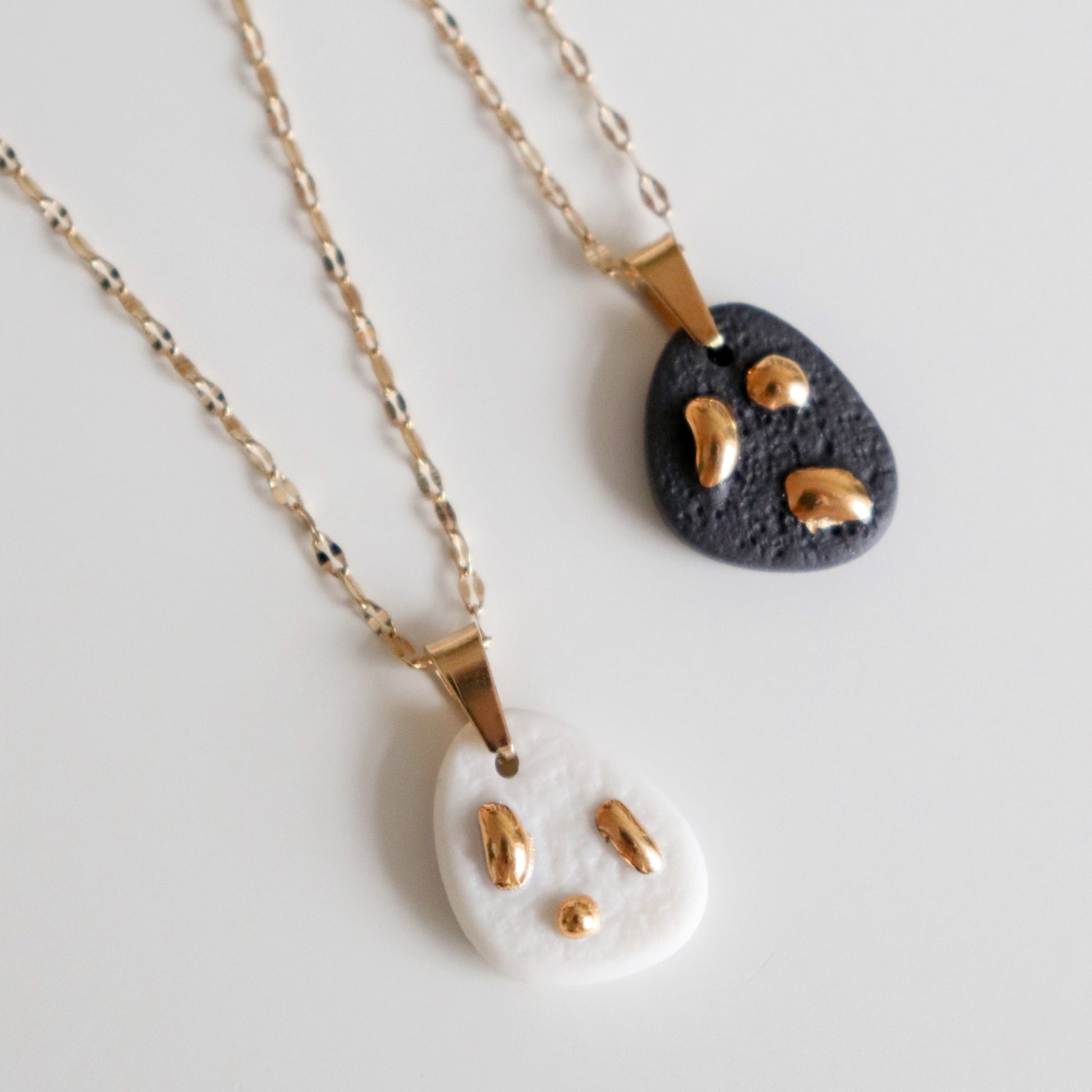 Two necklaces with matte porcelain pendants on a light gray background