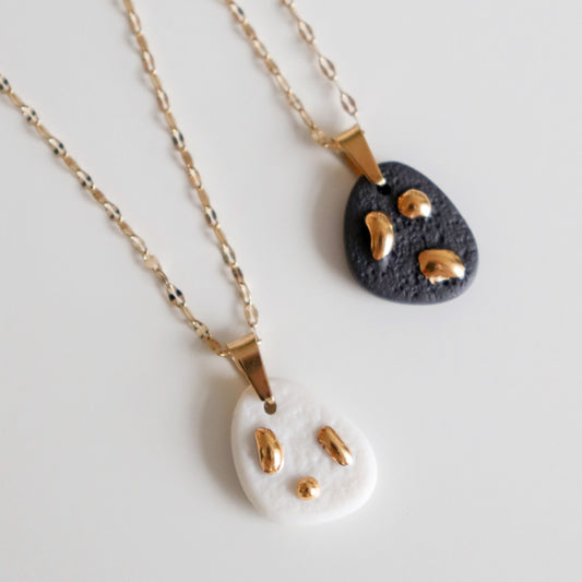 Two necklaces with matte porcelain pendants on a light gray background
