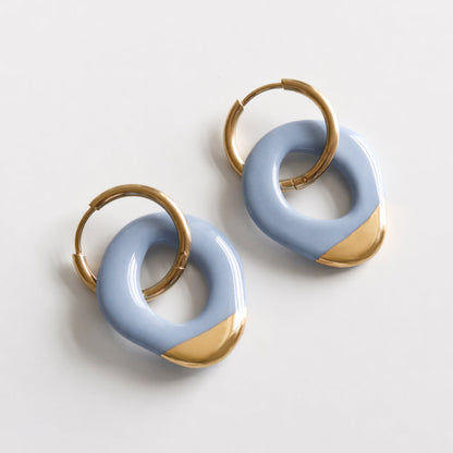 Pair of blue and gold hoop earrings on a light gray background