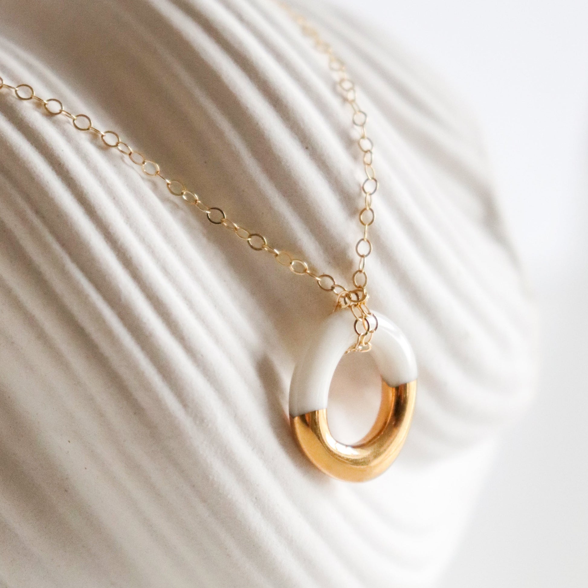 Gold necklace with a white pendant dipped in gold
