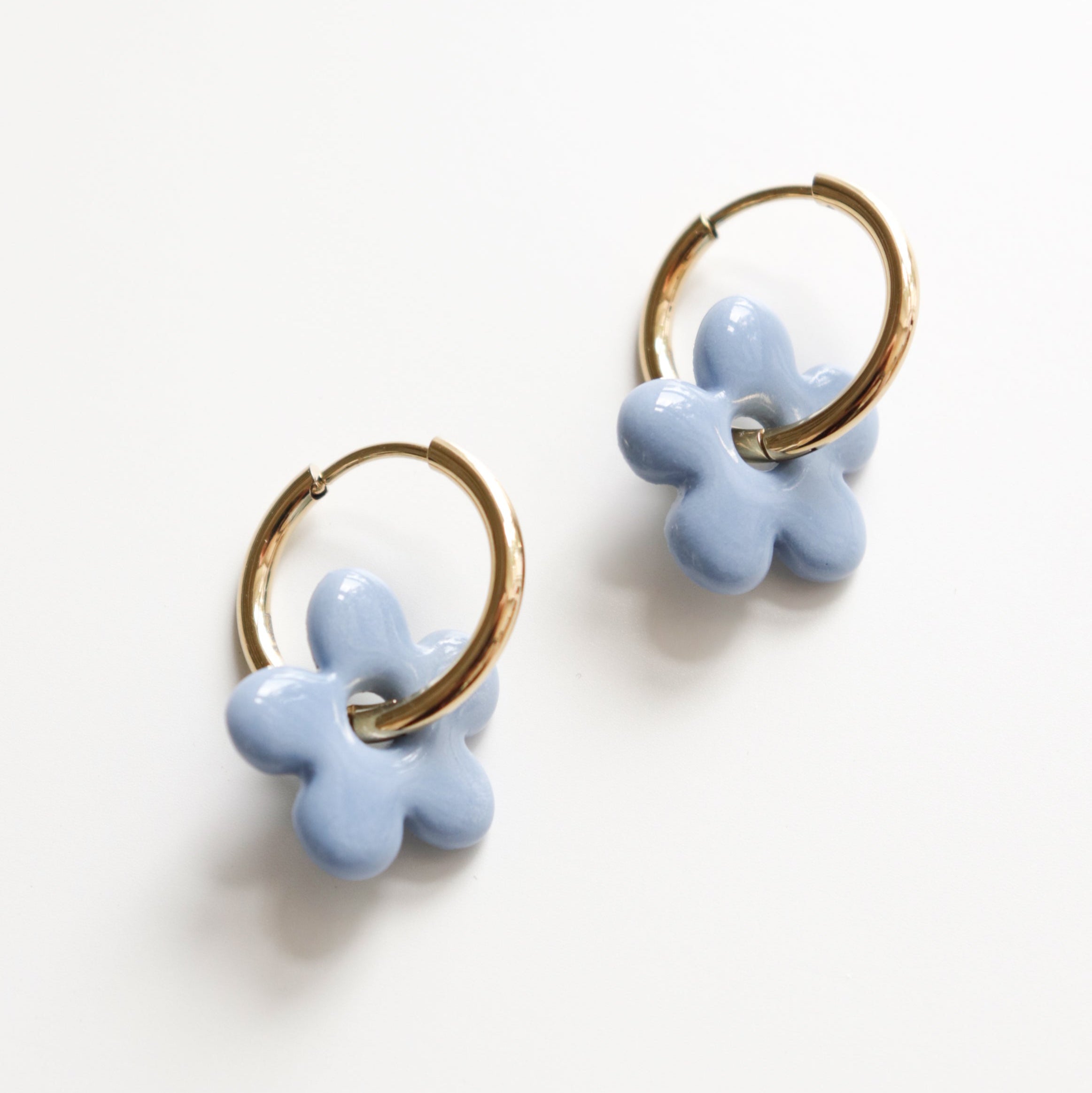 Pair of light blue flower-shaped hoop earrings on a white background