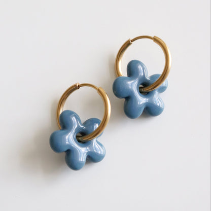 Pair of blue flower-shaped earrings with gold hoops on a white background
