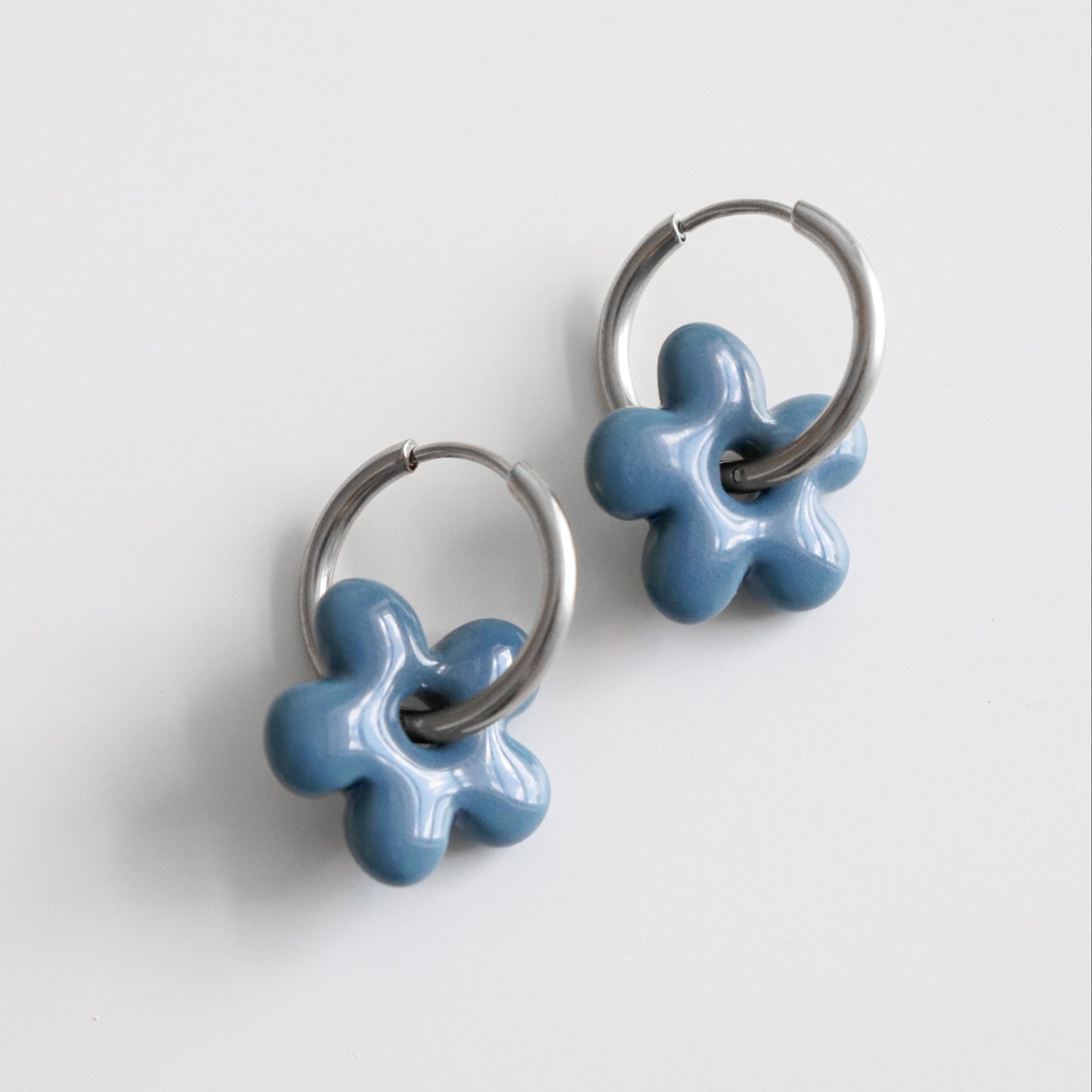 Pair of blue flower-shaped earrings on a light gray background
