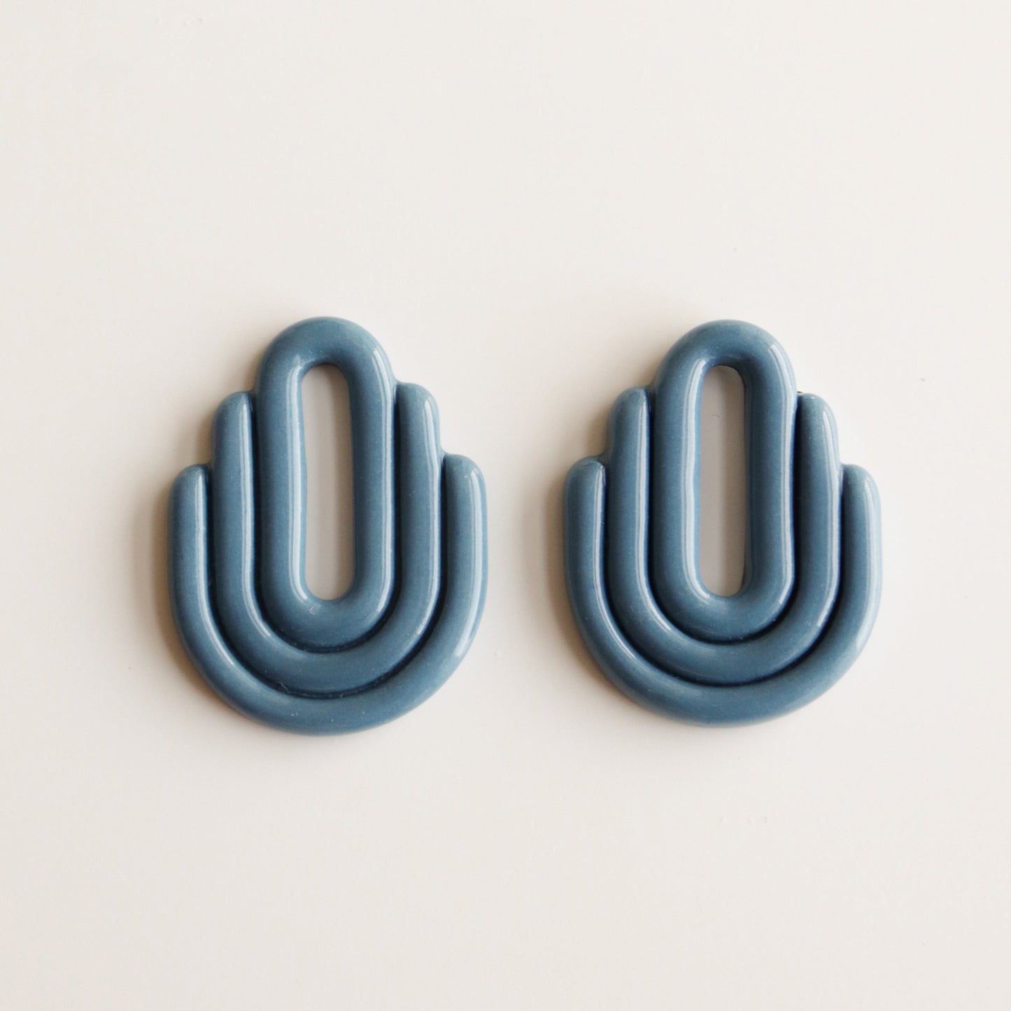 Art Deco Earrings from Rozenthal Jewelry—two blue, arched pieces with three rounded tiers each, evoking abstract hands. Placed side by side on white, theyre perfect as sustainable, unique handmade jewelry.