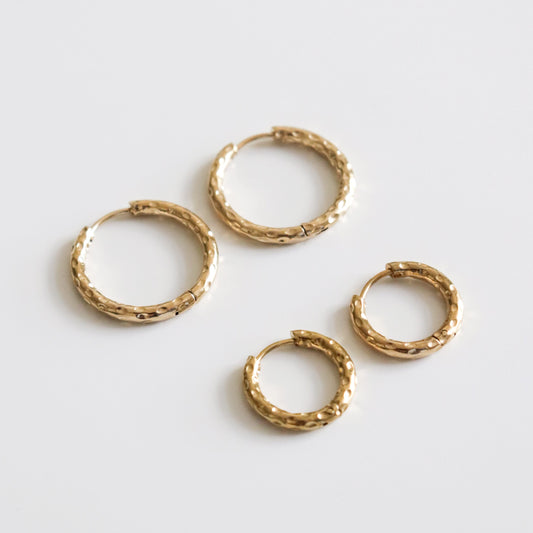 Set of textured gold hoop earrings on a light gray background
