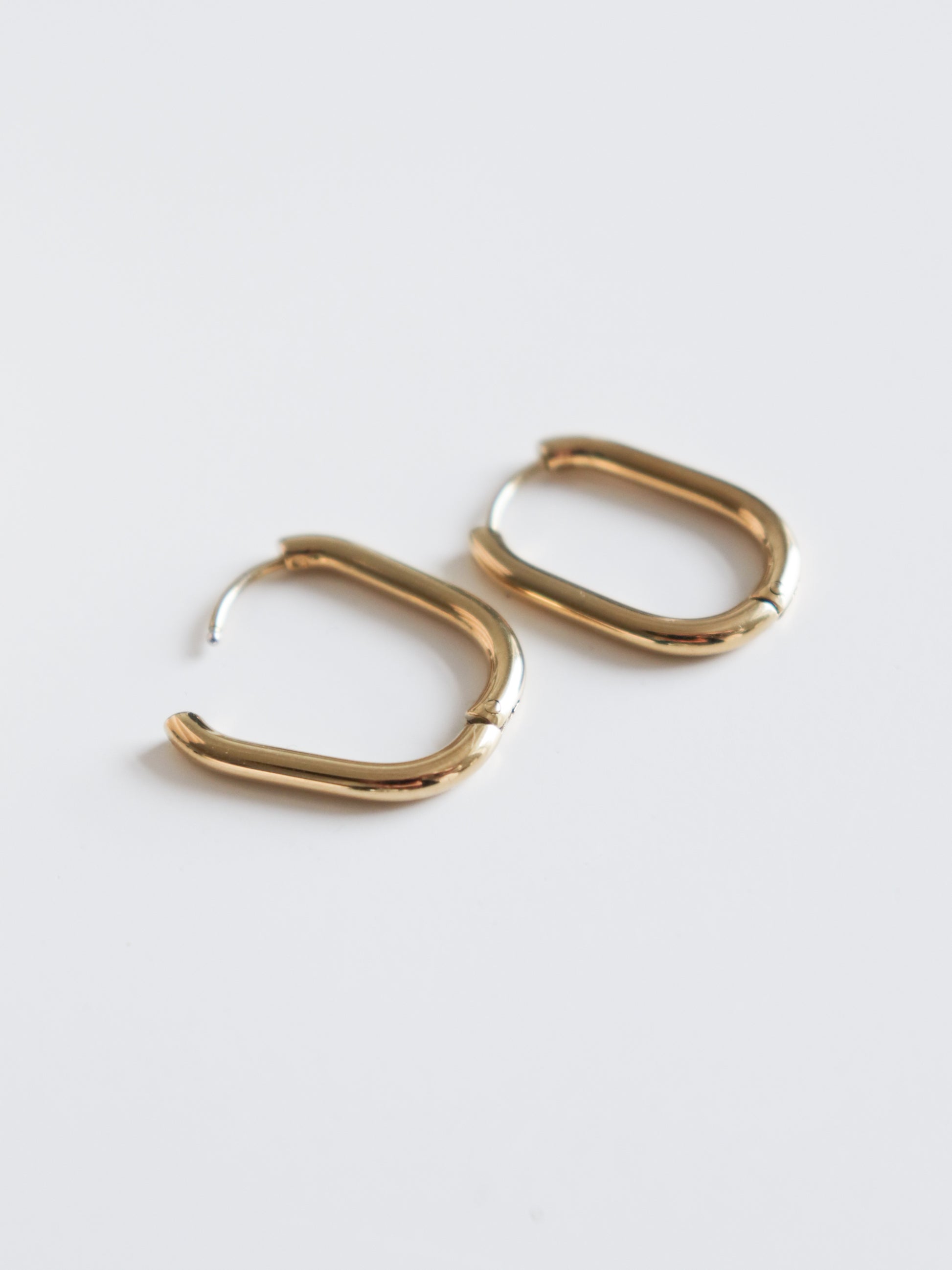 The Rozenthal Jewelry Large Hoops are gold-colored, rounded rectangular stainless steel earrings shown on a plain white background.