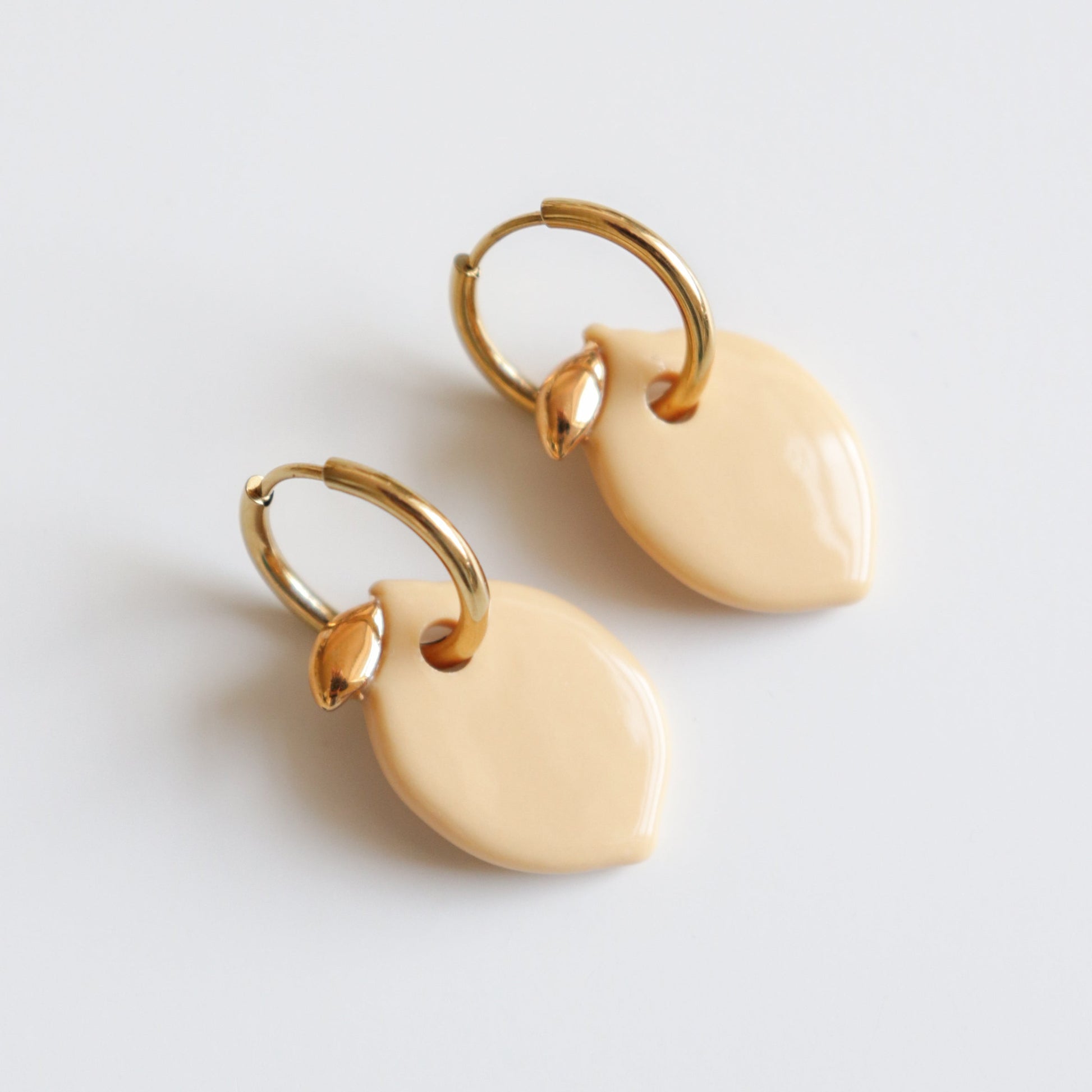 Pair of gold hoop lemon earrings on a light gray background