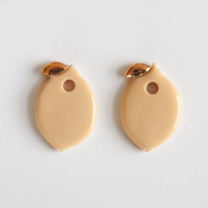 Two beige lemon charms with gold accents on a light gray background