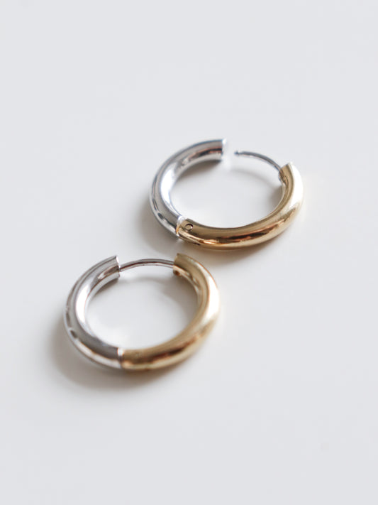 Two Gold and Silver Hoops by Rozenthal Jewelry rest side by side on a white surface; each earring features a smooth, shiny finish with half silver and half gold tones.